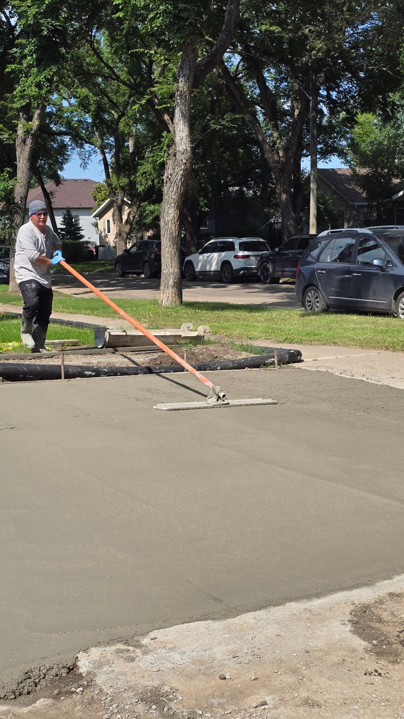 Bull float smoothing a fresh concrete driveway surface in a Saskatoon neighbourhood