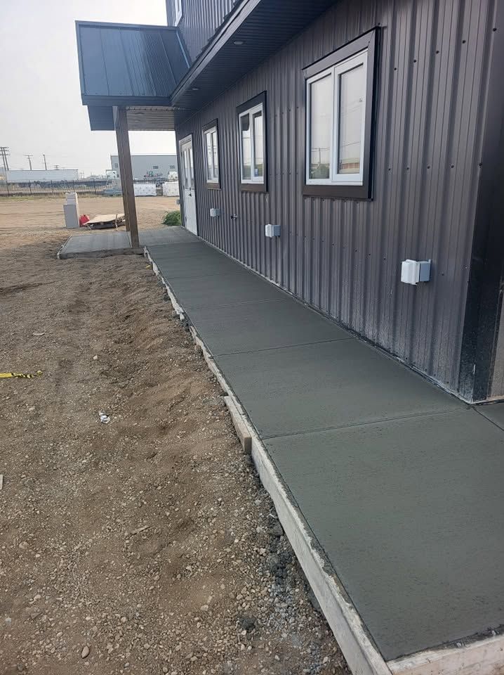 Concrete sidewalk poured alongside a commercial metal-clad building in Saskatoon