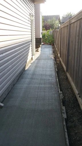 Concrete sidewalk running between a house and fence line