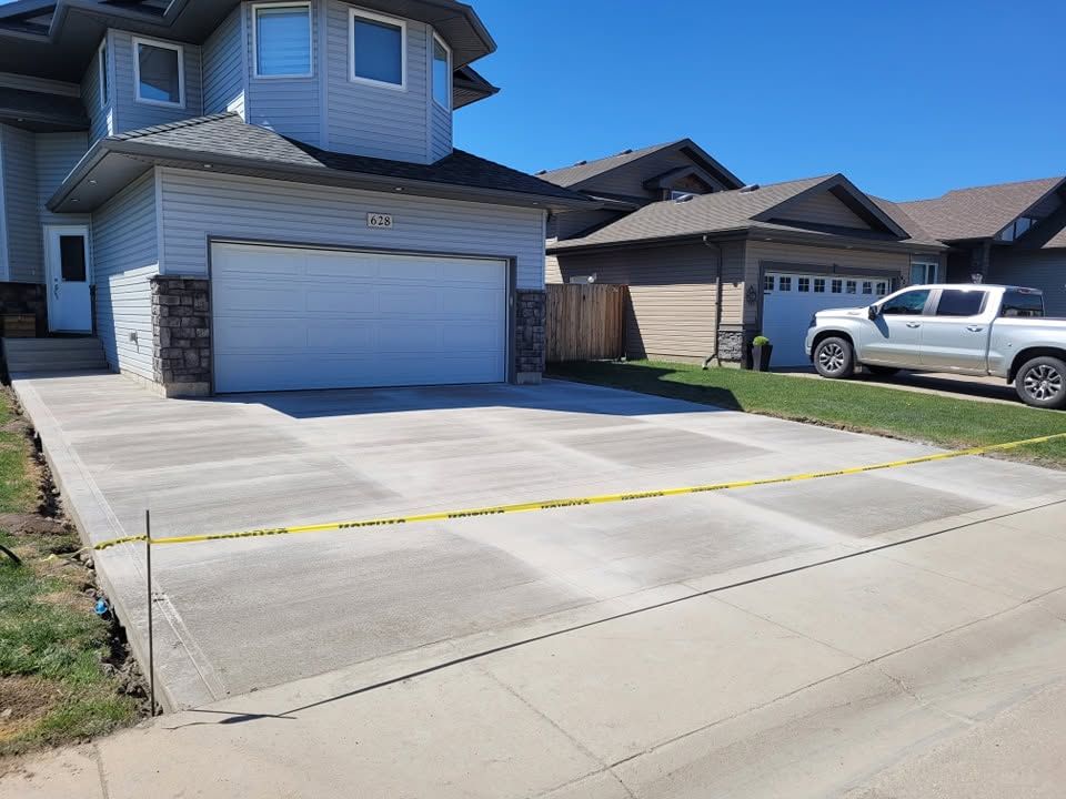 Finished broom-finish concrete driveway in front of a Saskatoon home with double garage