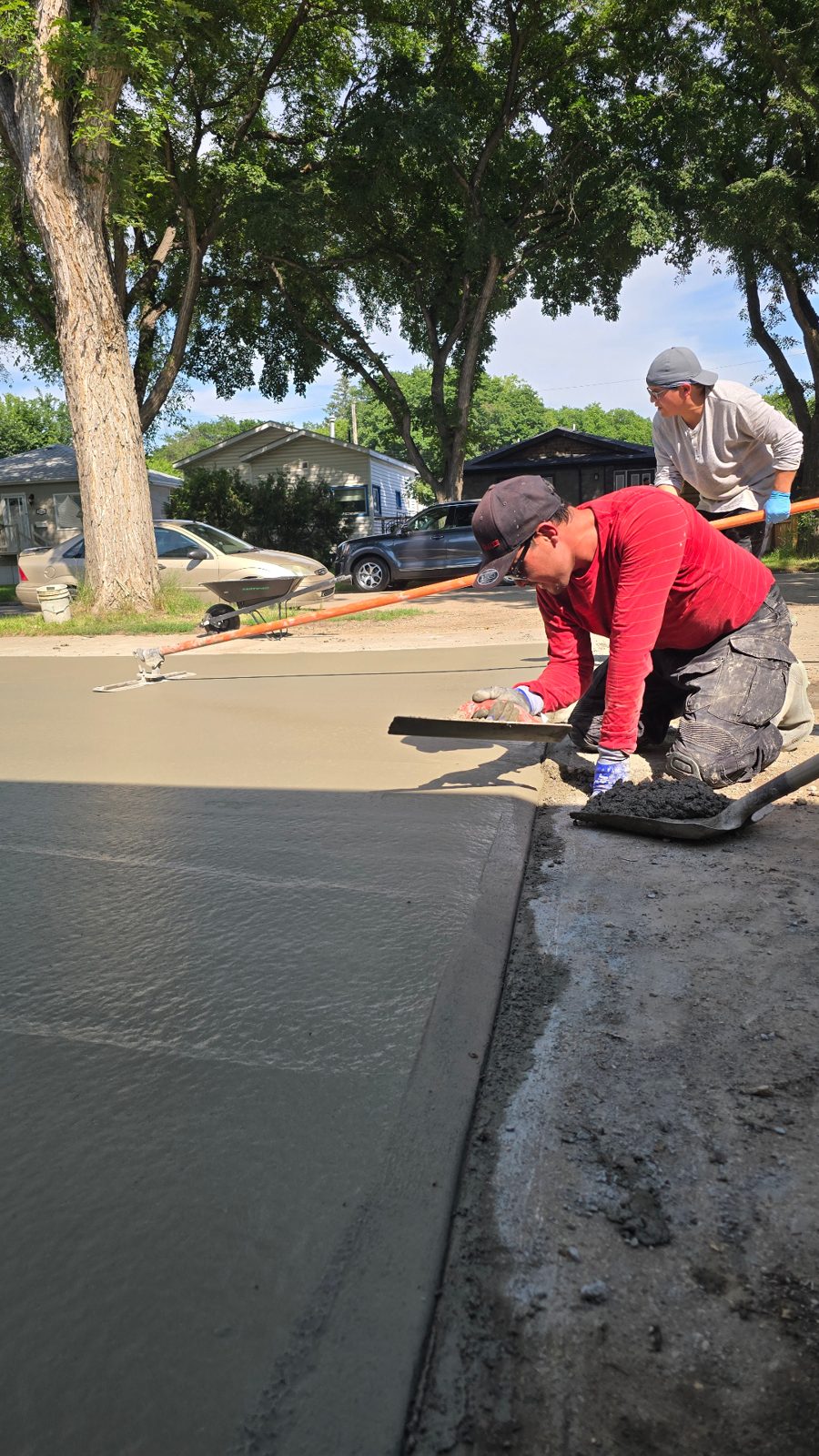 AB Concrete Finishing crew troweling and edging a fresh driveway pour in Saskatoon