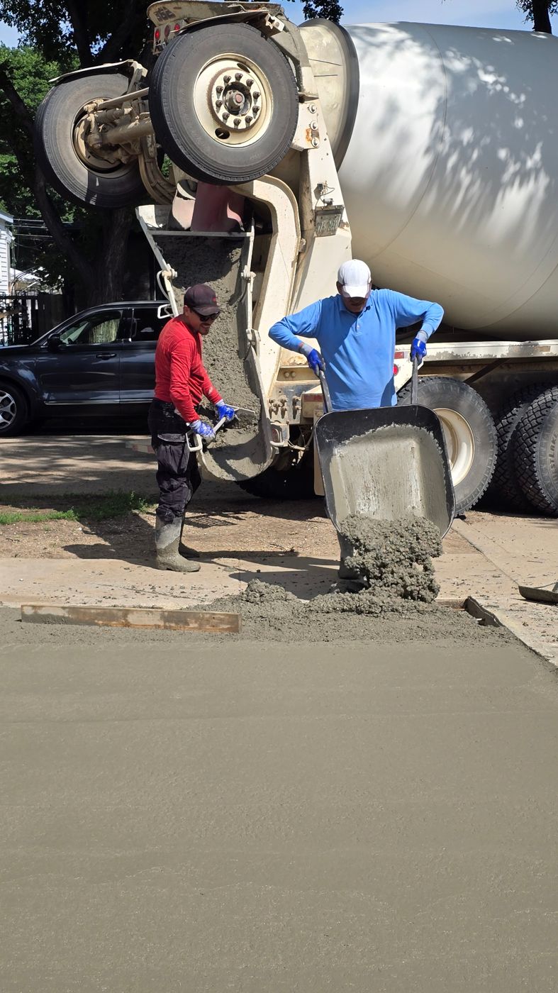 Two crew members placing and moving concrete during a driveway pour