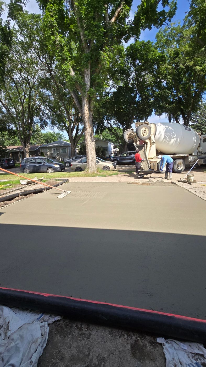 Freshly poured and floated concrete driveway pad with mixer truck on site
