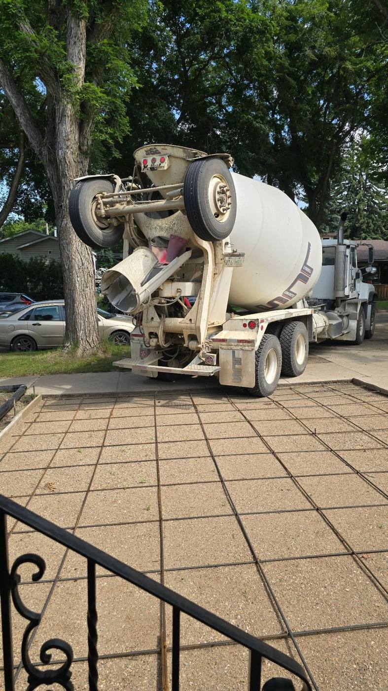 Mixer truck positioned over a rebar-reinforced driveway pad ready to pour