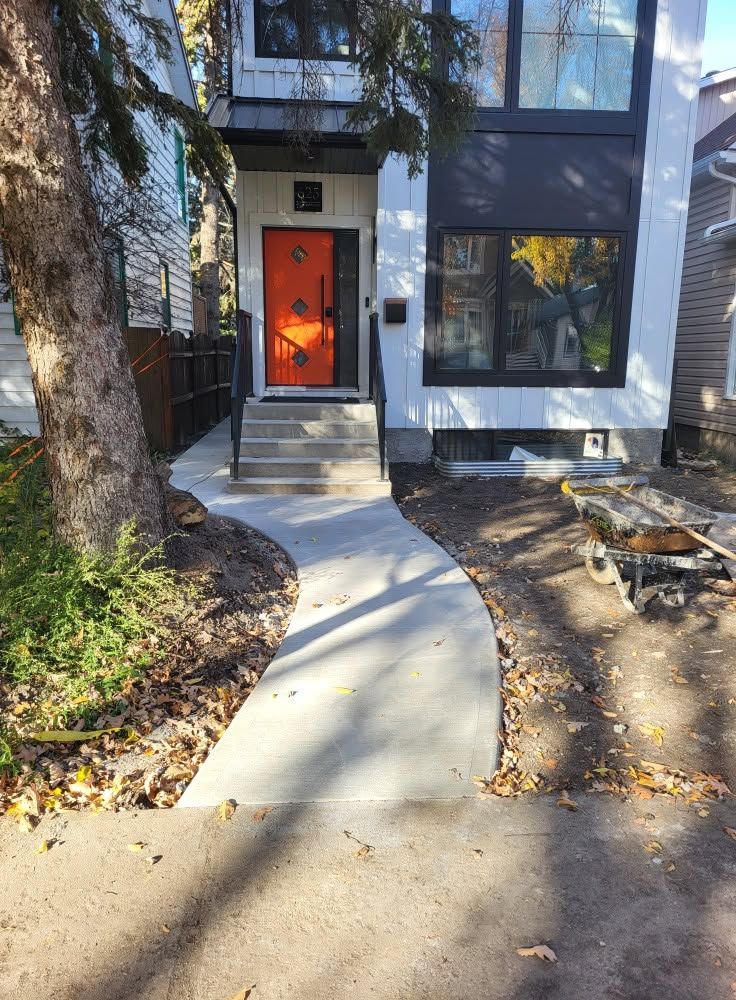 Curved concrete walkway leading to a modern front entry with orange door in Saskatoon