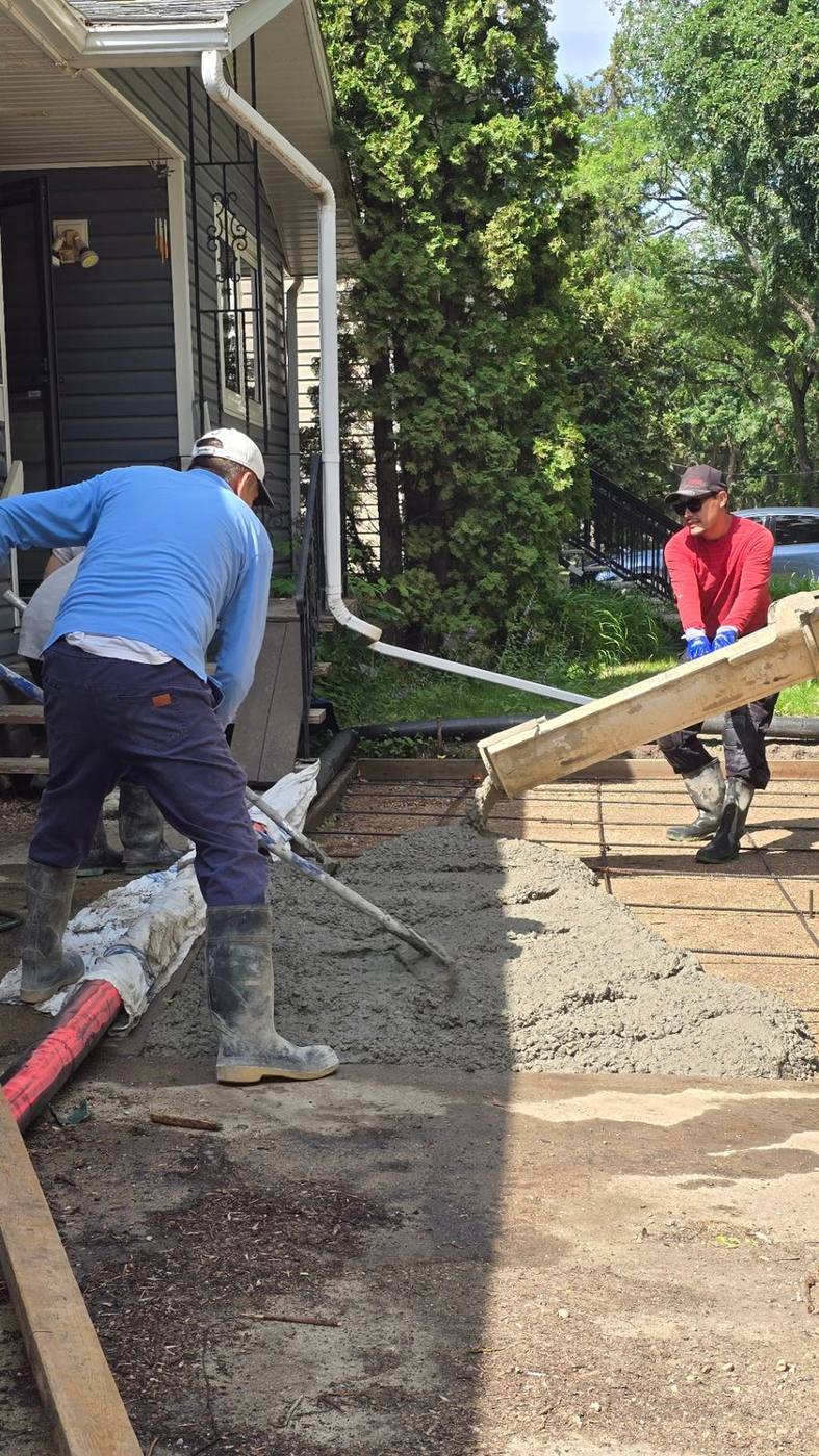 Crew pouring a fresh concrete driveway alongside a Saskatoon home