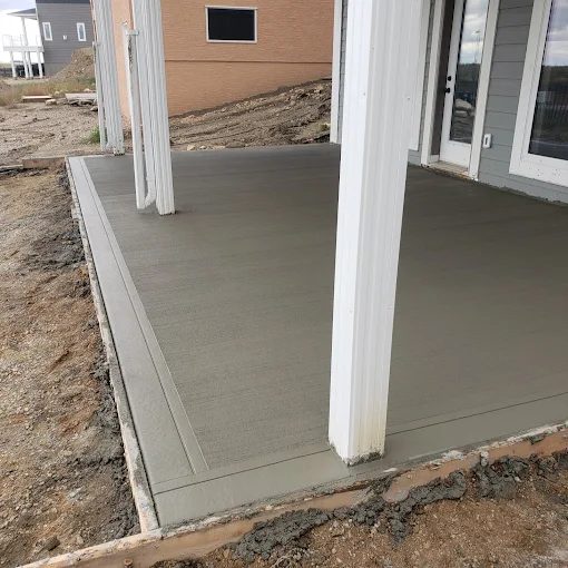 Broom-finish concrete patio with decorative border along a Saskatoon home