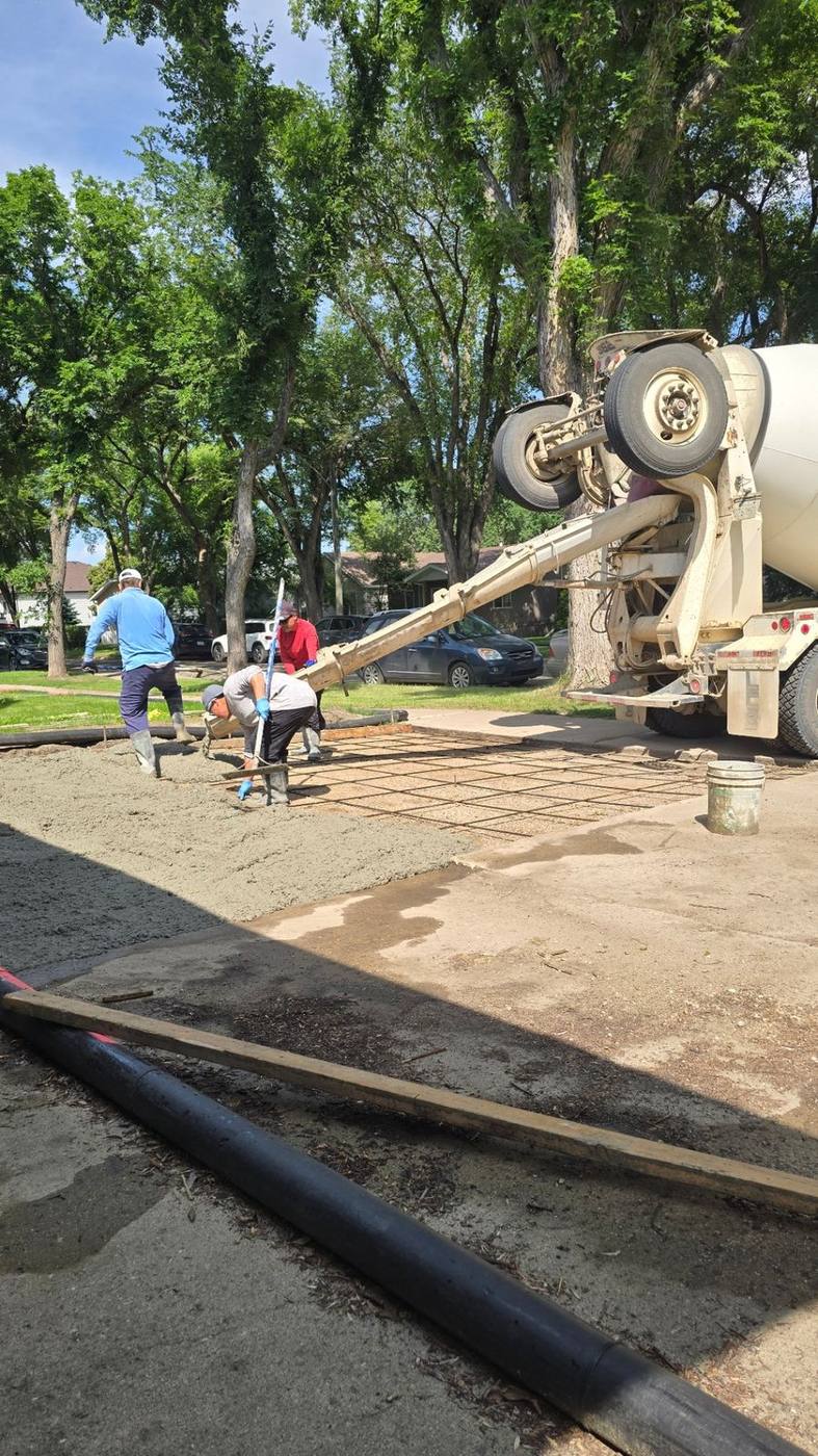 Workers screeding freshly poured concrete across a reinforced pad