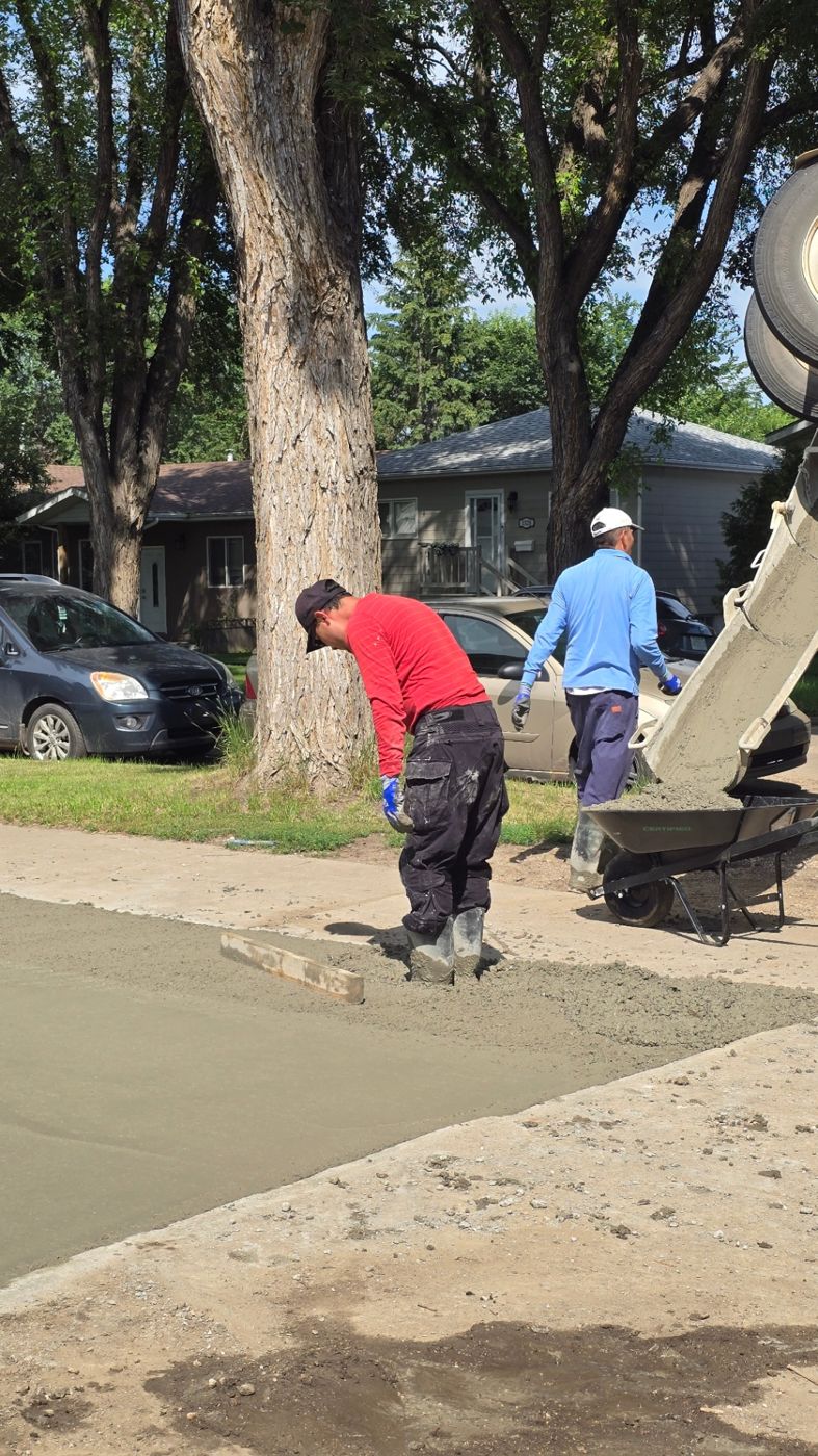 Finisher edging a freshly poured concrete driveway alongside a Saskatoon home