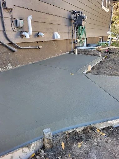 Side-yard concrete pad finished around utility connections